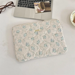 Detailed quilted texture of floral laptop sleeve with delicate embroidery and branding