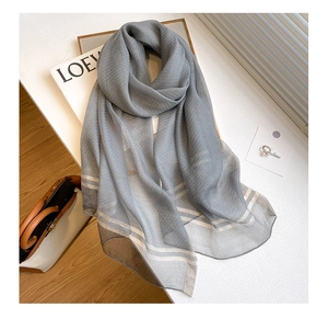 Detail of grey silk wool scarf featuring sparkling silver stripes on sheer textured fabric