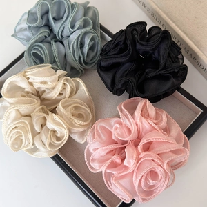 Detailed close-up of four organza floral scrunchies in gray-green, black, beige, and pink