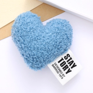 Close-up of blue plush heart accessory with soft faux shearling texture and woven label