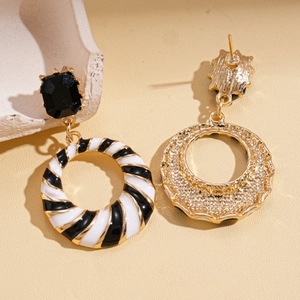 Detailed view of vintage gold hollow geometric earrings with black and white spiral patterns