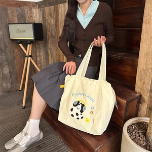 Detail of cream canvas tote bag featuring cute puppy embroidery and puppy land text