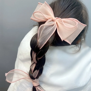 Detail of pink organza bow hair clip with long ribbons woven into a braided hairstyle