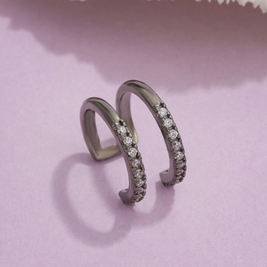 Black double-layer ear cuff with white zircon stones on purple textured backdrop
