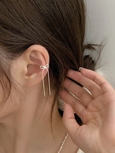 Detailed view of silver bow zircon tassel ear cuff on model, elegant non-piercing jewelry