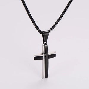 Macro detail of silver and black layered stainless steel cross pendant with metal chain