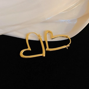 Detailed macro view of gold hollow heart-shaped earrings with high-gloss mirror finish
