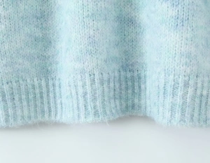Detailed macro view of light blue mohair knit sweater featuring ribbed hem and soft texture