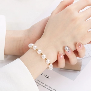Elegant pearl bracelet with gold beads worn by a model against a minimalist background