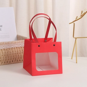 Red kraft gift bag with window and smiling eye design plus black handles for birthdays
