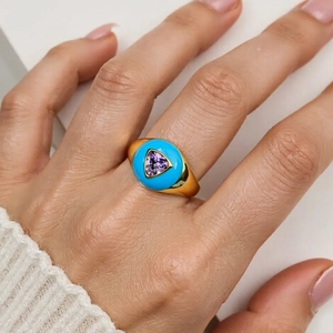 Detailed view of a gold ring with turquoise enamel and purple triangle zircon on finger