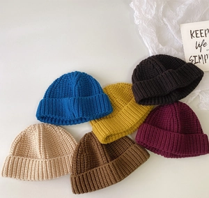 Vista plana de seis gorros de punto coloridos para niños en azul, amarillo y tonos tierra