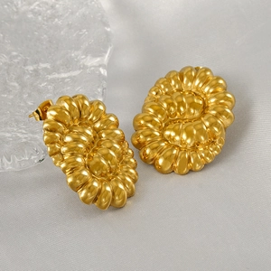 Gros plan sur des boucles d'oreilles torsadées dorées 18 carats sur un tissu gris