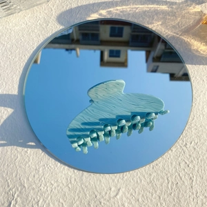 Détail d'une pince à cheveux en acétate bleu clair à motif marbré sur un miroir