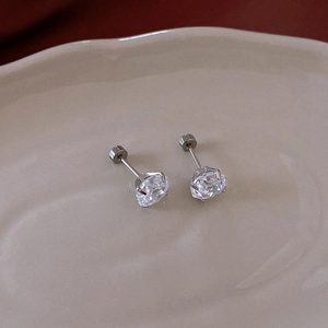 Detailed close-up of a silver round zircon stud earring placed on a ceramic tray
