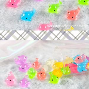 Close-up of colorful glowing mini dolphin resin figurines scattered on soft grey fabric