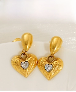 Detail of 18k gold heart earrings with hammered texture and sparkling center stone