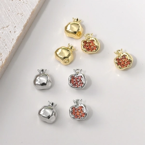 Macro shot of 14K gold plated pomegranate charms with red zircon inlay and smooth finish