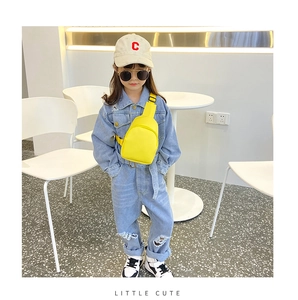 Detail of yellow nylon chest bag paired with light blue denim overalls for kids