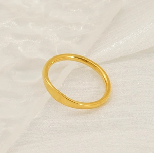 Close-up of minimalist 18K gold plated titanium steel band ring on white textured fabric