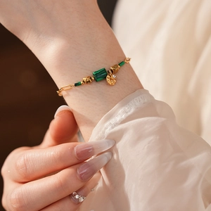 Gros plan d'un bracelet vintage doré orné de pierres carrées vertes de style malachite