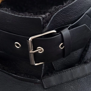 Detalle de cuero granulado negro con hebilla de metal plateado y forro interior cálido