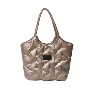 Borsa tote trapuntata dorata con cuciture a rombi ed etichetta nera FASHION BAG su bianco