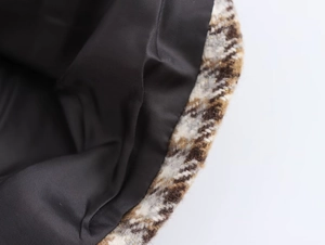 Details des Tweed-Mantelstoffs mit schwarz-weißem Karomuster und Goldseidenfäden