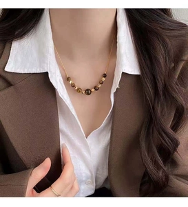 Close-up of Maillard brown beaded necklace worn with a white shirt and brown blazer.