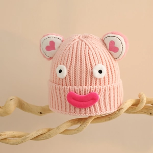 Détail du bonnet en tricot rose avec de grands yeux de dessin animé et cœurs rouges