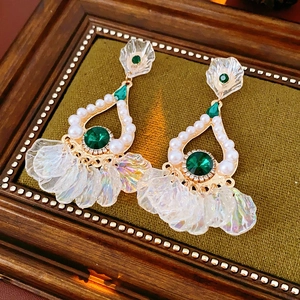 Dettaglio di orecchini di lusso con smeraldi, perle e cristalli in cornice vintage