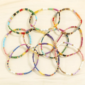Macro shot of colorful Tila bead stretch bracelets stacked on a premium cream silk cloth