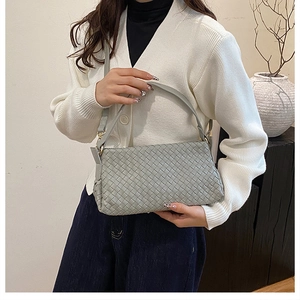 Gros plan sur la texture en cuir tressé gris et la boucle métallique du sac à bandoulière