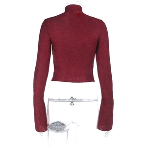 Primer plano de un crop top de encaje rojo oscuro con textura jacquard floral y cuello alto