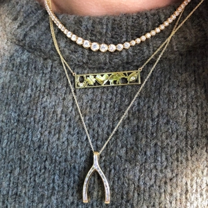 Gros plan de colliers dorés à trois rangs avec pendentifs trèfle et breloque