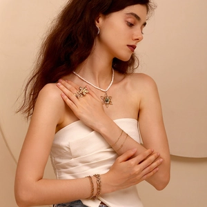 Close-up of 14K gold plated flower jewelry set with pearl necklace and matching rings