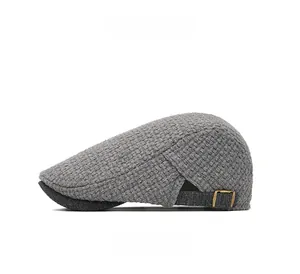 Close-up of grey knit newsboy cap showing textured waffle pattern and bronze metal buckle