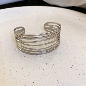 Detail of minimalist multi-layer silver line open bangle on a ceramic display