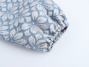Detail von hellblauem Jacquard-Stoff mit elastischen Bündchen an einem Kleid mit Laternenärmeln