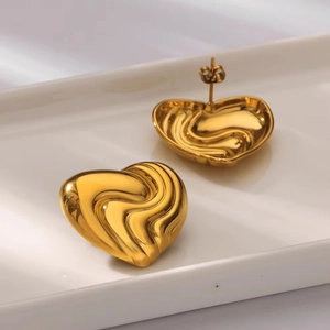 Detailed view of 18K gold plated heart earrings with unique wavy texture on white tray