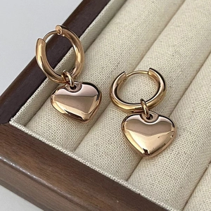 Détail des boucles d'oreilles à pendentif cœur en or rose dans un coffret à bijoux en bois