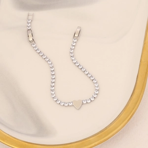 Detailed view of silver zircon bracelet with central heart charm on decorative plate