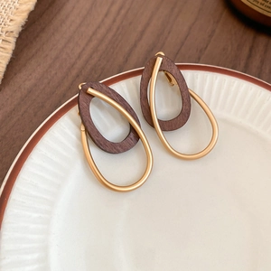 Vue macro de boucles d'oreilles rétro avec anneaux en bois foncé et métal doré mat