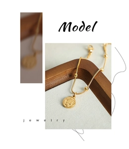 Detail of a vintage gold-plated snake chain bracelet with a portrait coin pendant