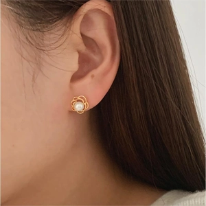 Detail of 925 silver camellia flower earrings with white pearl inlay worn by a model