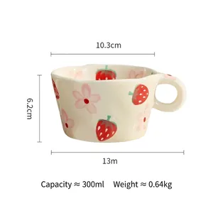 Detail of hand-painted strawberry ceramic mug with wavy rim and chunky handle