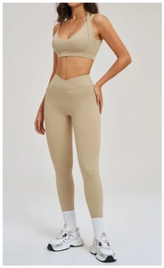 Dettaglio dei leggings yoga con vita a V, tasche laterali e reggiseno sportivo beige
