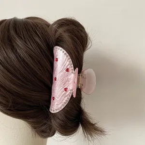 Détail d'une pince à cheveux rose en acétate avec cœurs rouges et strass fins