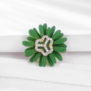 Macro view of green enamel daisy brooch with gold hollow center and white zircons
