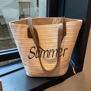 Large beige woven straw tote bag with brown leather handles and Summer embroidery